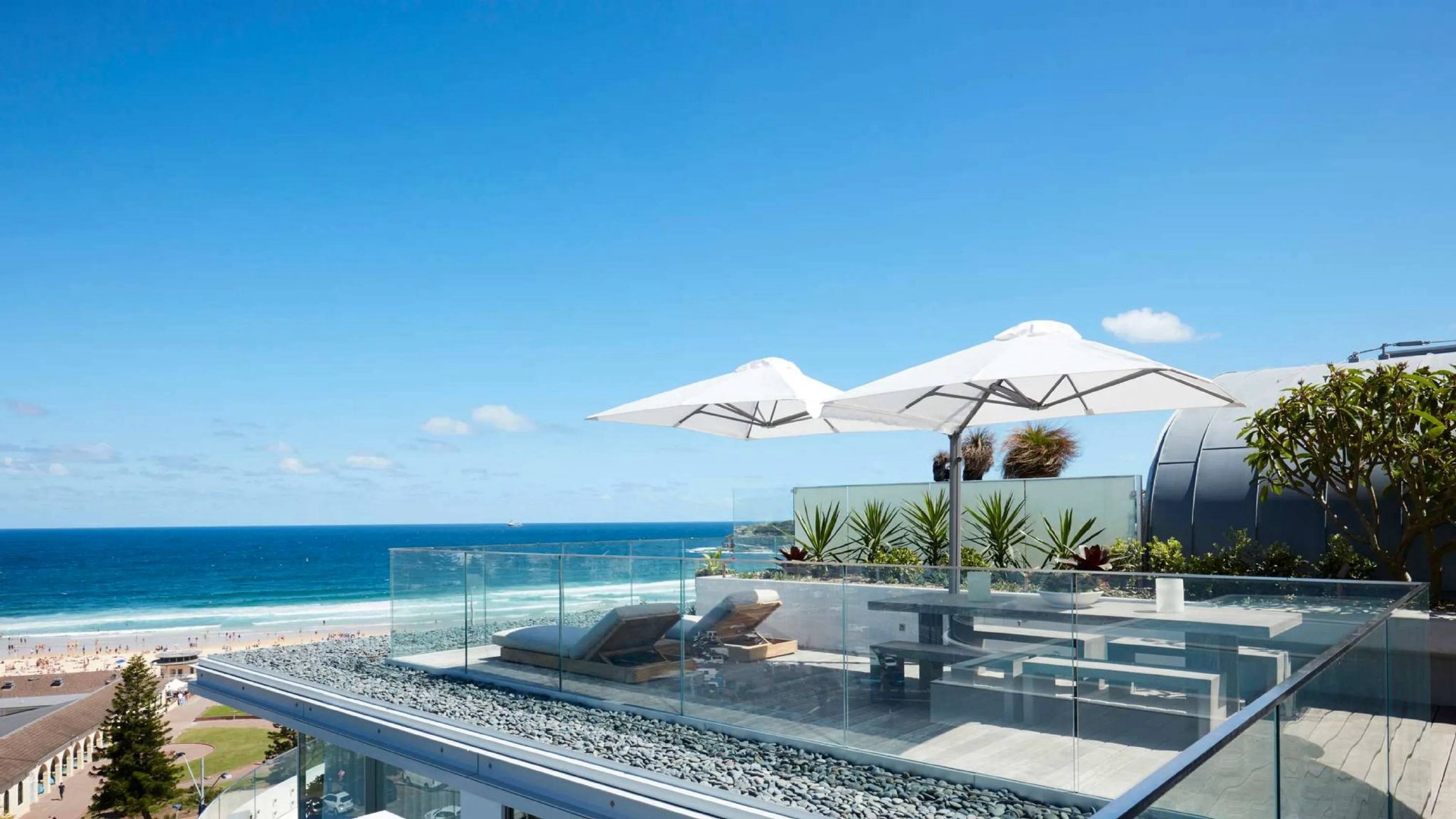 Rooftop terrace with sun loungers and umbrellas overlooking the ocean