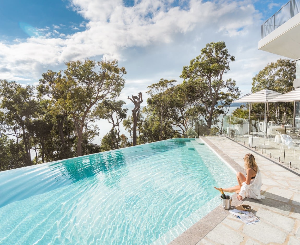 Infinity pool overlooking bushland with a guest seated at the edge