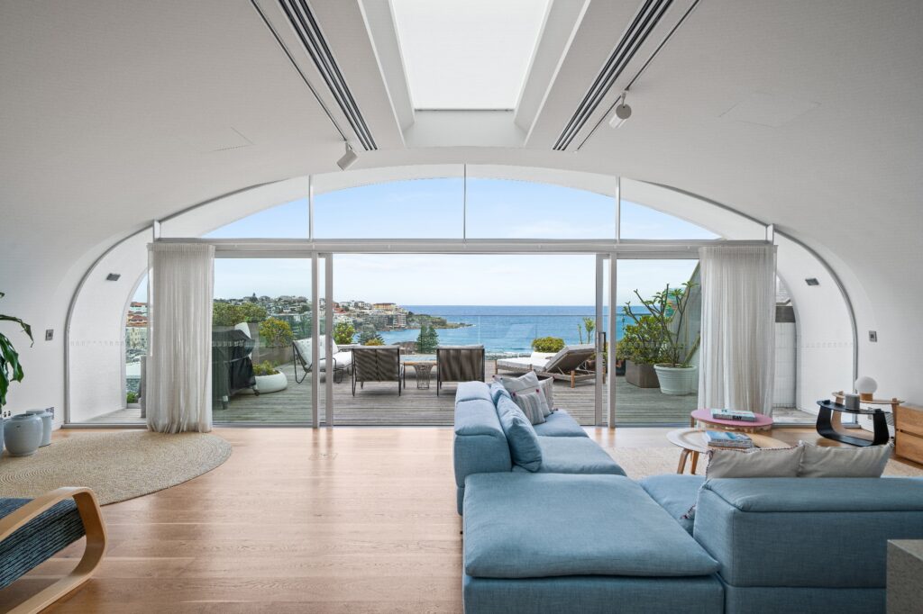 Living room with a blue sofa opening onto a terrace above the ocean at Bondi