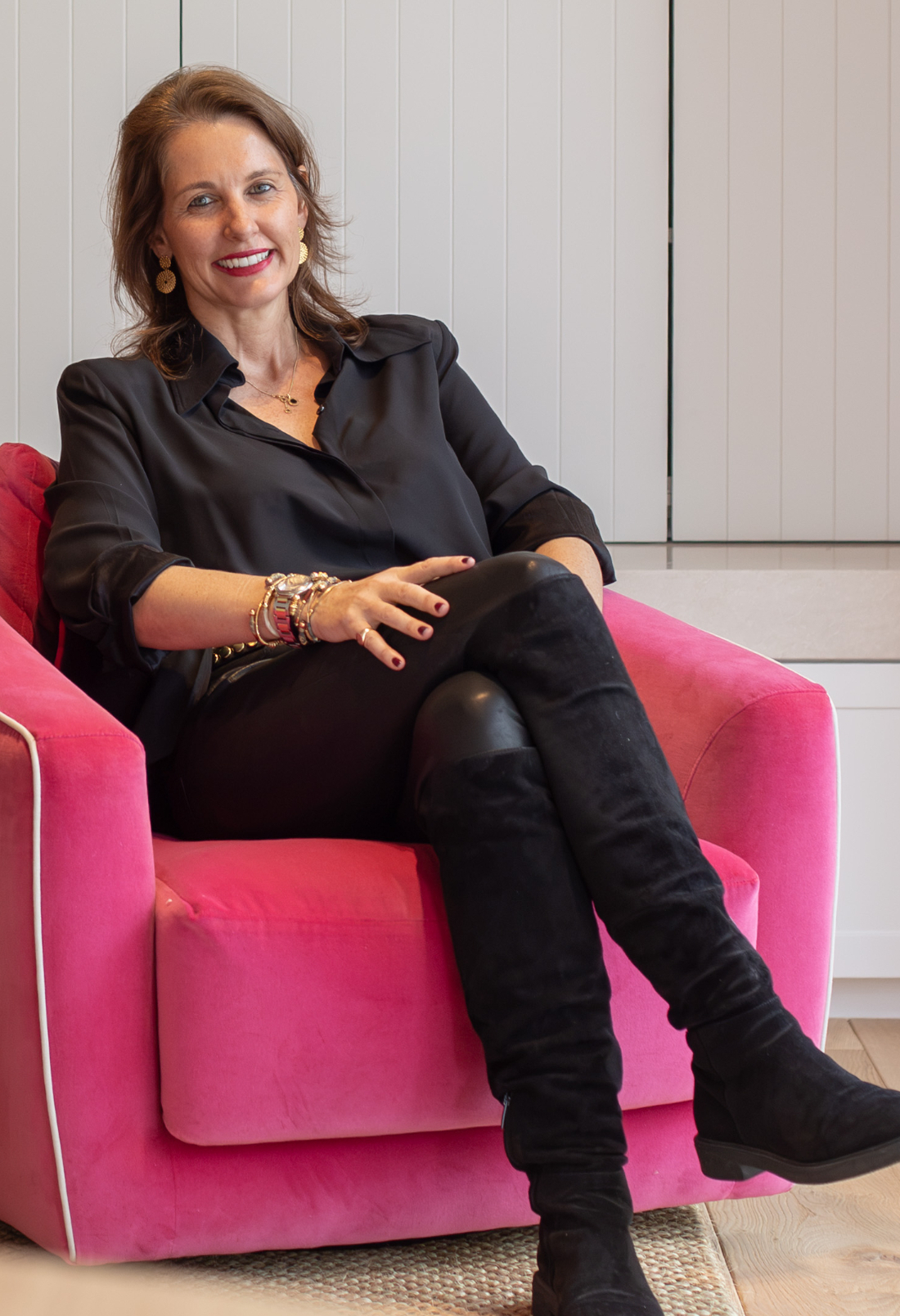 Property owner seated in a pink velvet armchair in her living room