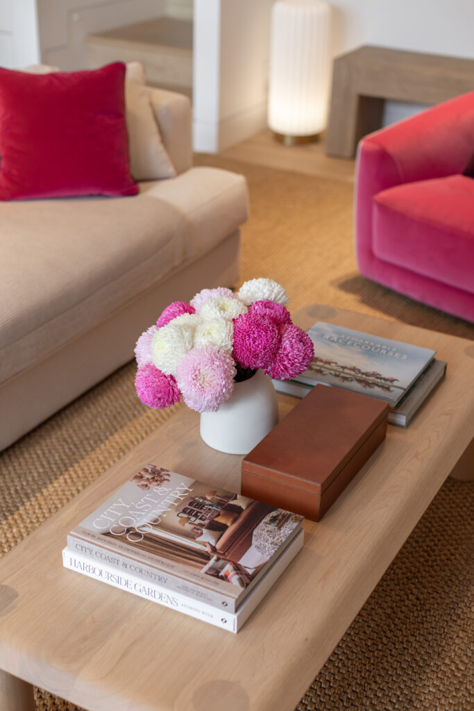 Pink and white flowers and design books on the oak coffee table