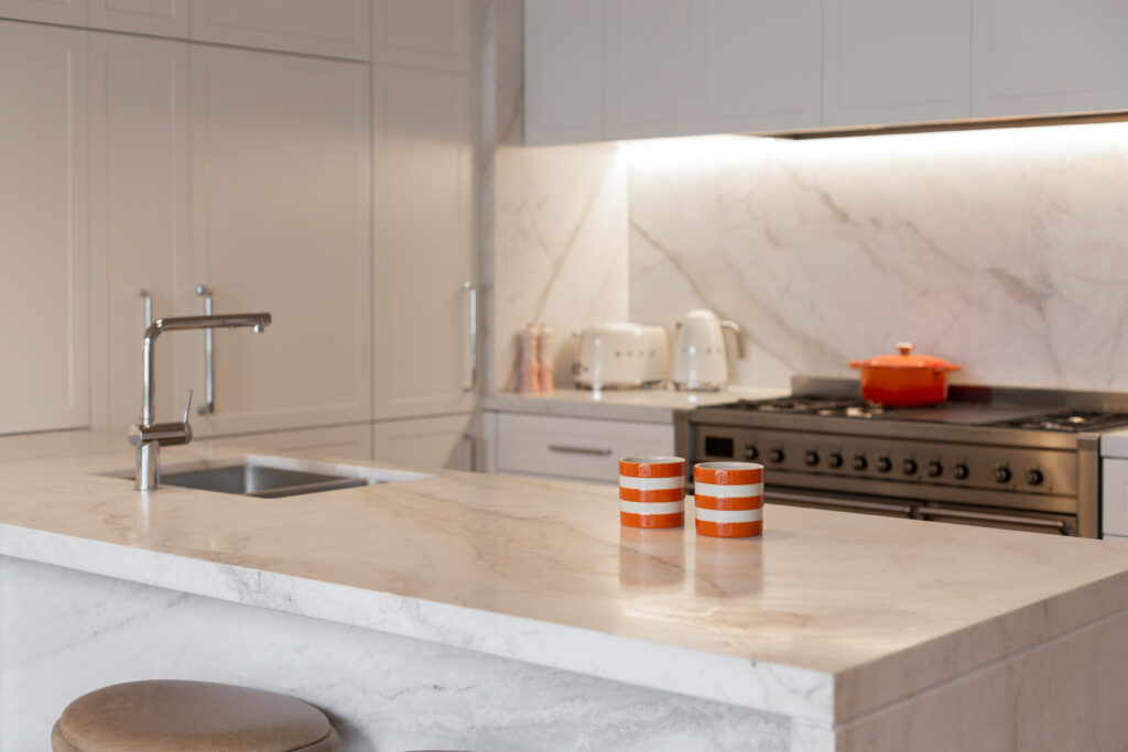 Marble kitchen island with two orange striped cups, the cooker behind