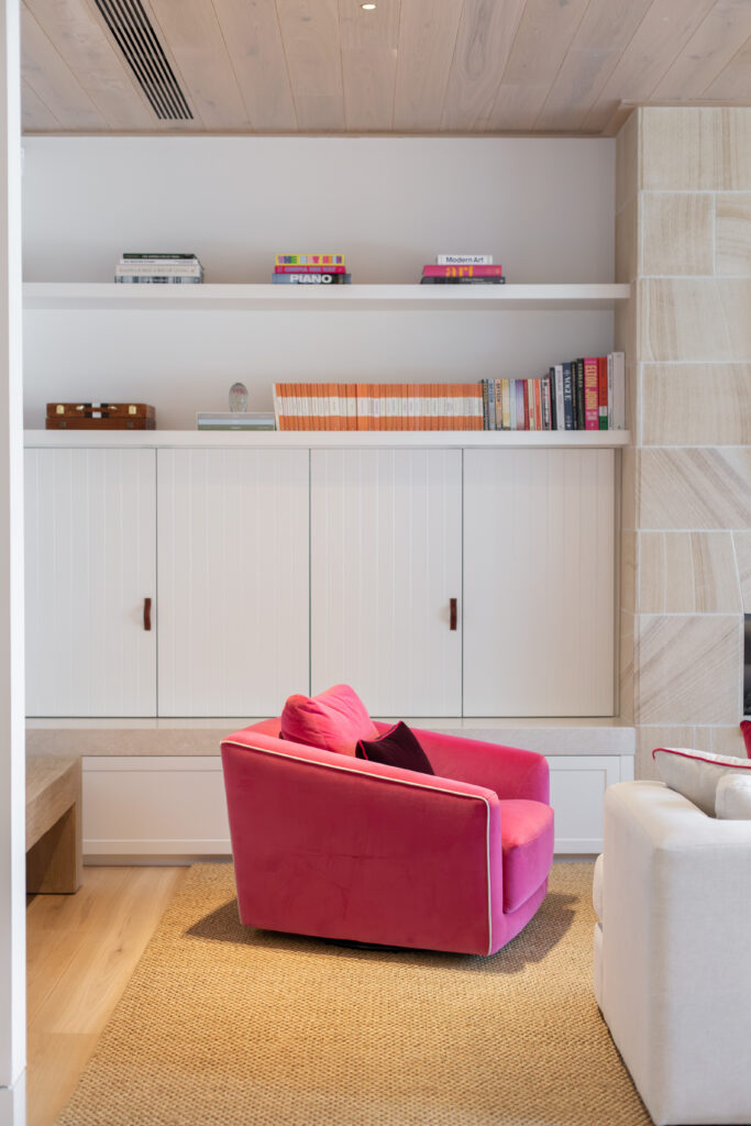 Pink velvet armchair in front of white panelled cabinets and bookshelves